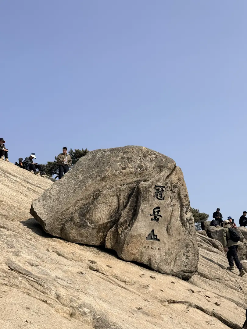 Gwanaksan summit stone marker with hikers on granite slope